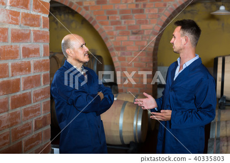 two speaking men in uniforms standing in cellar with wine woods two speaking men in uniforms standing in cellar with wine woods 40335803