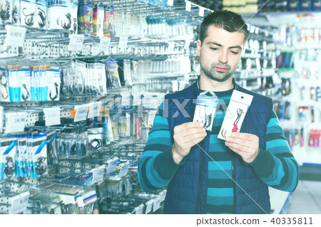 Fisherman looking fishing hooks for fishing in the sports shop 40335811