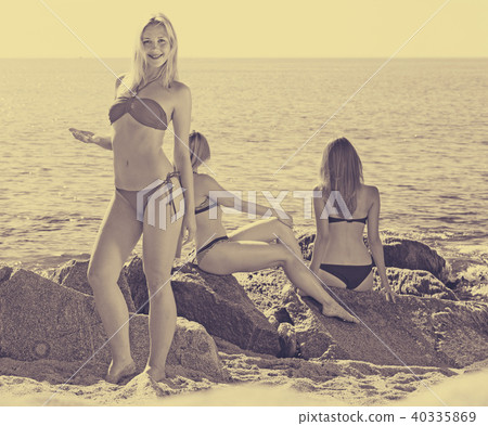 Portrait of cheerful young woman standing on rocky beach 40335869