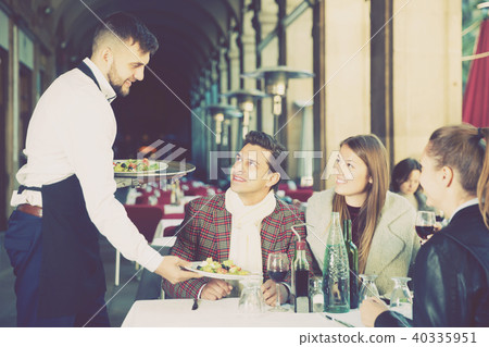 polite waiter serving guests at terrace restaurant 40335951