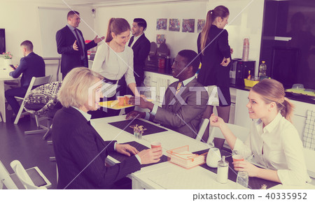 Smiling business coworkers enjoying free time and talking, relaxing Smiling business coworkers enjoying free time and talking, relaxing 40335952