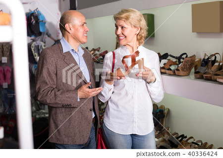 Mature couple picking shoes in boutique. Mature couple picking shoes in boutique. 40336424