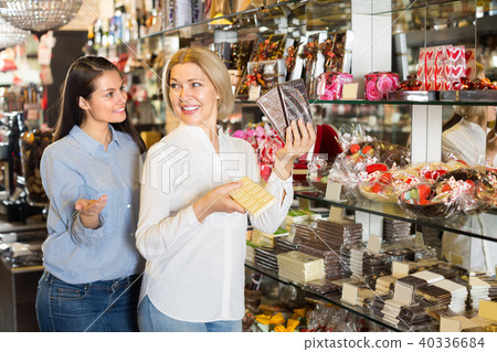 Happy women buying chocolate bars . Happy women buying chocolate bars . 40336684