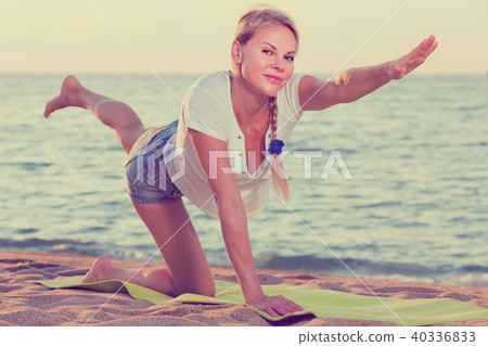 Smiling adult woman in white T-shirt is doing excercises on endurance Smiling adult woman in white T-shirt is doing excercises on endurance 40336833