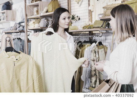 Female seller showing yellow sweater to client in the modern shop 40337092
