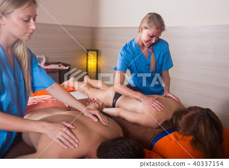 Woman masseuse is doing massage for couple Woman masseuse is doing massage for couple 40337154