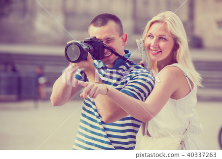 Two cheerful tourists holding camera in hands 40337263