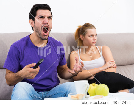 Disappointed girl on sofa while man watching tv Disappointed girl on sofa while man watching tv 40337463