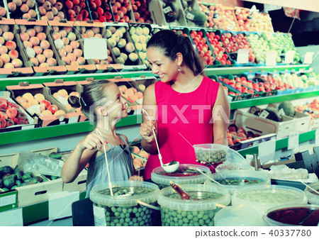Woman with girl buying pickled olives 40337780