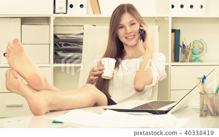 Female with bare feet on desk talking on phone Female with bare feet on desk talking on phone 40338419