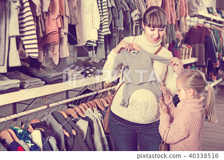 Pregnant mother and daughter choosing romper suit for baby in children’s clothes shop Pregnant mother and daughter choosing romper suit for baby in children’s clothes shop 40338516