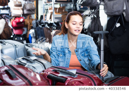 portrait of teenage girl picking new big plastic luggage bag with wheels in shop 40338546