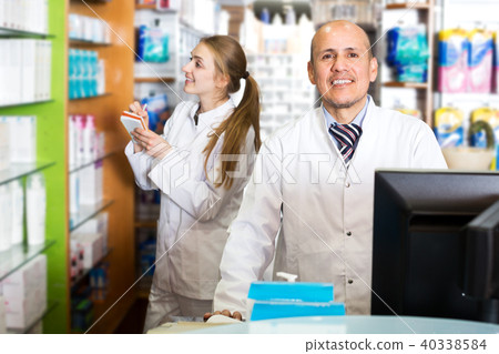 Pharmacist and assistant working at farmacy reception Pharmacist and assistant working at farmacy reception 40338584