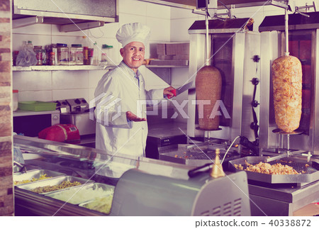 Cheerful mature man cook cutting kebab meat on kitchen Cheerful mature man cook cutting kebab meat on kitchen 40338872