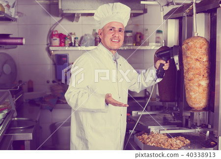 mature chef slicing kebab in fast food. mature chef slicing kebab in fast food. 40338913
