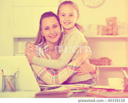 schoolgirl hugging her young mother 40339138