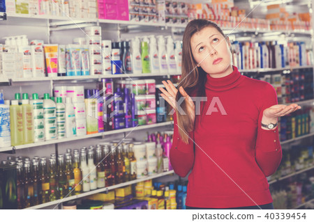 Portrait of upset woman who is dissatisfied of quality her hair in the store. Portrait of upset woman who is dissatisfied of quality her hair in the store. 40339454