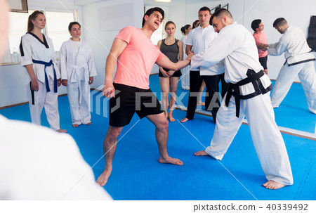 Coach explaining painful hold in taekwondo class Coach explaining painful hold in taekwondo class 40339492