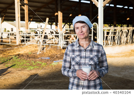 Adult female is standing with glass of cow milk Adult female is standing with glass of cow milk 40340104