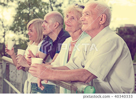 mature people with plastic cup standing in the park mature people with plastic cup standing in the park 40340333