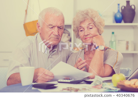 Worried mature man and woman analyzing bills Worried mature man and woman analyzing bills 40340676