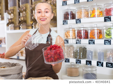 Young woman is offering dried flowers of Hibiscus in container 40340841
