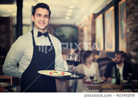 Professional waiter holding serving tray for restaurant guests Professional waiter holding serving tray for restaurant guests 40340899