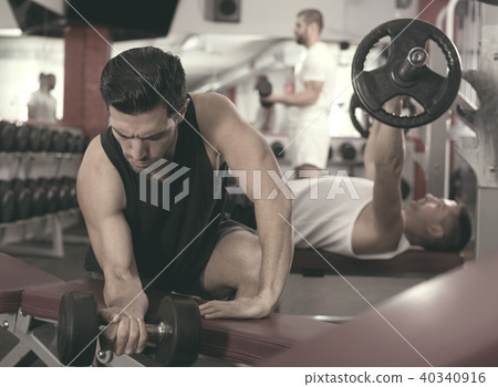 Man exercising with dumbbells in gym Man exercising with dumbbells in gym 40340916