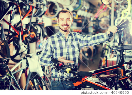 man checks bicycle handlebar in shop when choosing bike man checks bicycle handlebar in shop when choosing bike 40340990