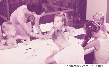 Glad girl and kids drawing on lesson with help of teacher Glad girl and kids drawing on lesson with help of teacher 40340999