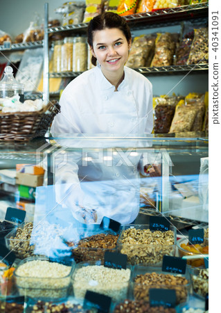 Young merchant is pouring on nuts into bag 40341091