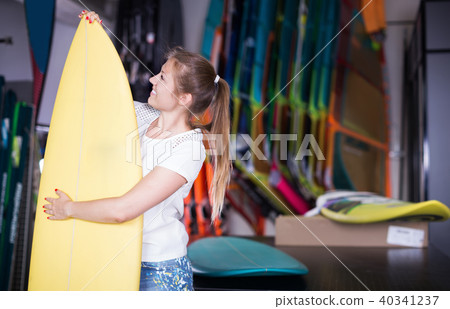 Girl who is choosing new surfboard in nautical store Girl who is choosing new surfboard in nautical store 40341237