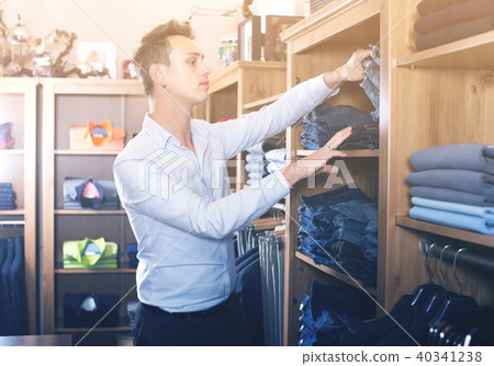 Brunette man deciding on new trousers Brunette man deciding on new trousers 40341238