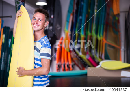 male is posing with surfboard in store on the beach. male is posing with surfboard in store on the beach. 40341287