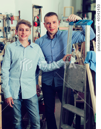 Portrait of adult father and son with stair in workshop. 40341430