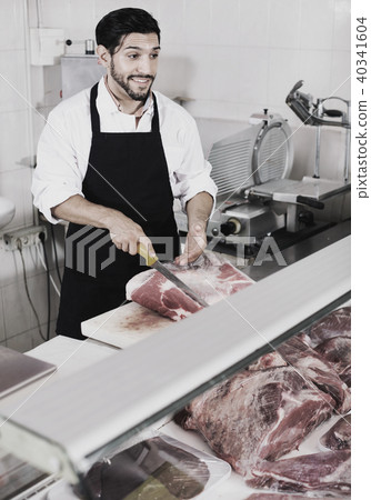 Adult butcher is cutting meat for seller to clients indoors. 40341604