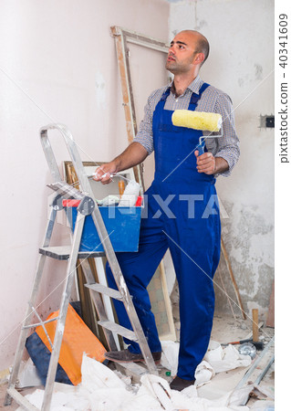 Male worker is standing with roller in uniform Male worker is standing with roller in uniform 40341609