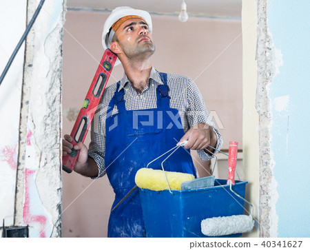 Portrait of constructor man which is standing with spirit level and bucket 40341627