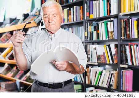 Mature male is choosing book for reading in free time Mature male is choosing book for reading in free time 40341685