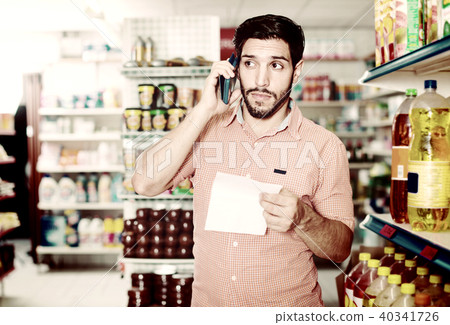 Portrait of adult male with note and smartphone in market. Portrait of adult male with note and smartphone in market. 40341726