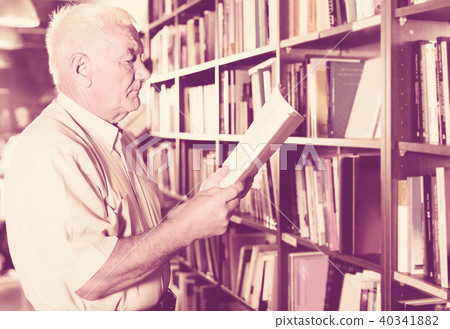 Old male is choosing book for reading in free time in bookstore. Old male is choosing book for reading in free time in bookstore. 40341882