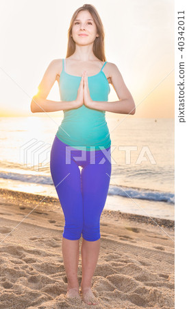 Female 20-25 years old is standing and practicing meditation in blue T-shirt Female 20-25 years old is standing and practicing meditation in blue T-shirt 40342011