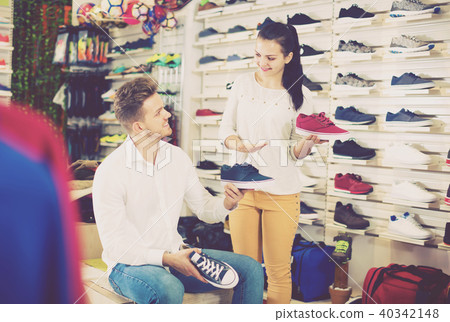 Young seller assisting man in choosing sneakers 40342148