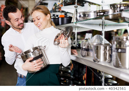 Couple examining various saucepans in dinnerware store Couple examining various saucepans in dinnerware store 40342561