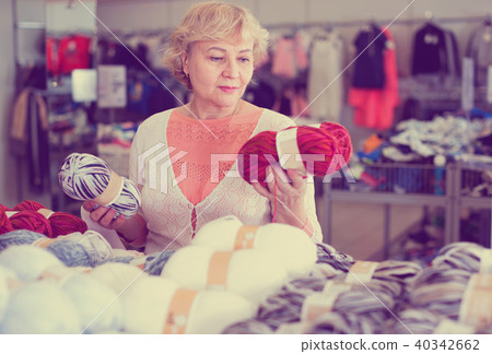Mature woman buyer choosing colored yarn for knitting on sale Mature woman buyer choosing colored yarn for knitting on sale 40342662
