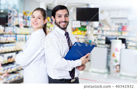 pharmacist and expert standing near shelves with medicines pharmacist and expert standing near shelves with medicines 40342932