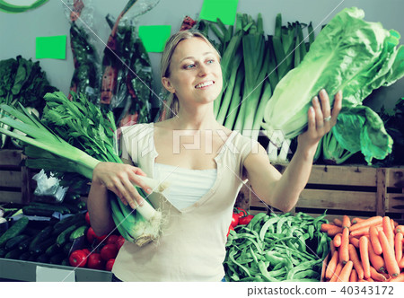 attractive young female customer holding fresh celery and leek attractive young female customer holding fresh celery and leek 40343172