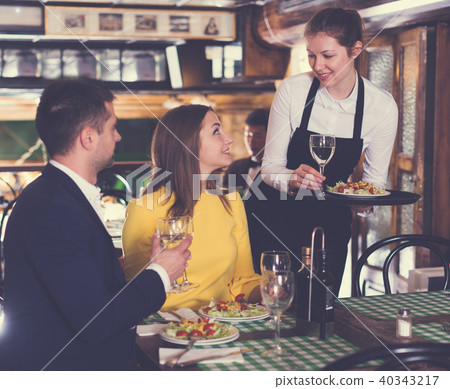 Woman waiter is brings order to couple who have dinner and drink wine 40343217