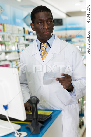 African American male pharmaceutist reading prescription of customer African American male pharmaceutist reading prescription of customer 40343270
