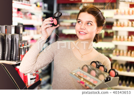 cheerful female customer deciding on make-up items in cosmetics shop cheerful female customer deciding on make-up items in cosmetics shop 40343653